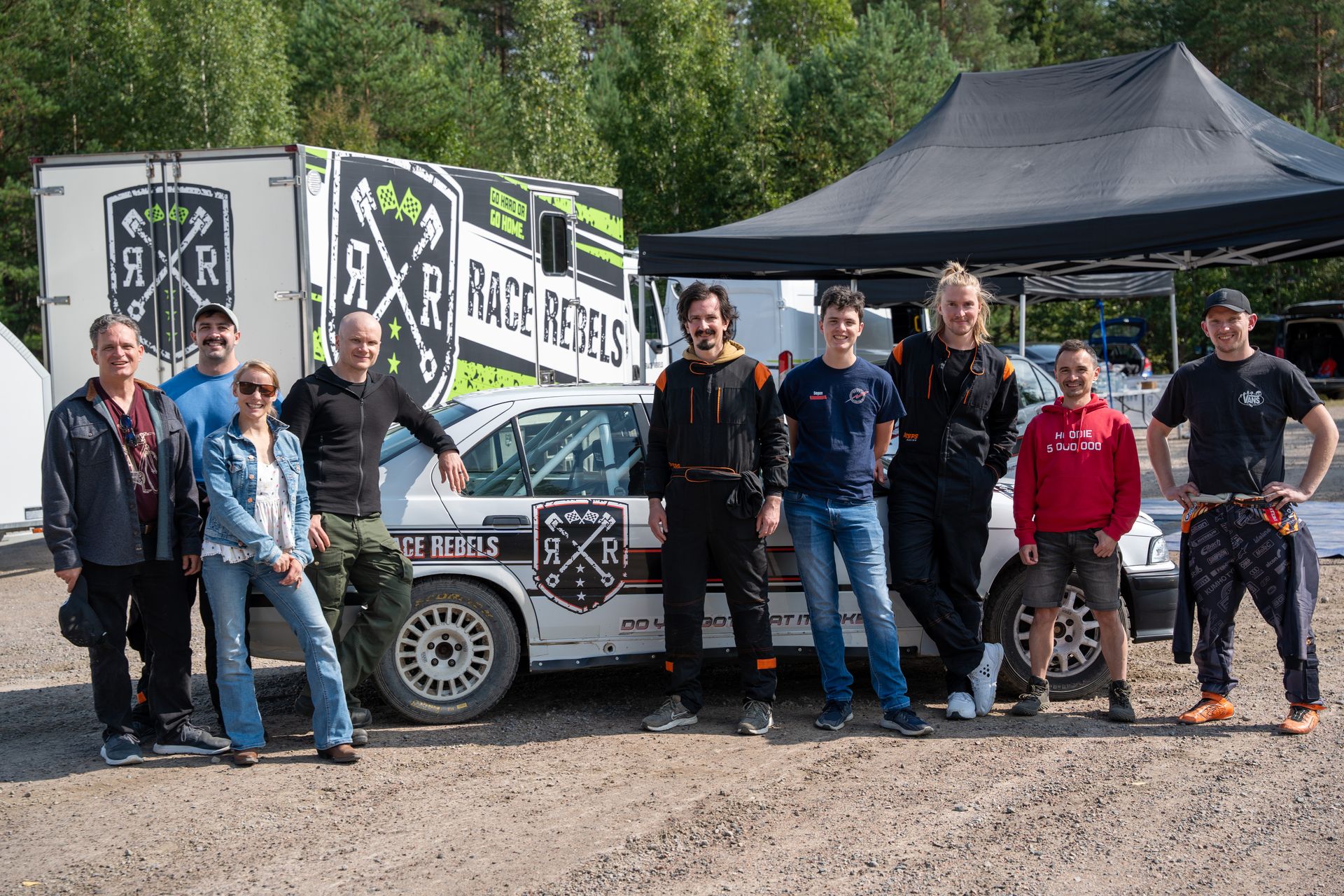 The rally-day group in front of a rally car and team trailer