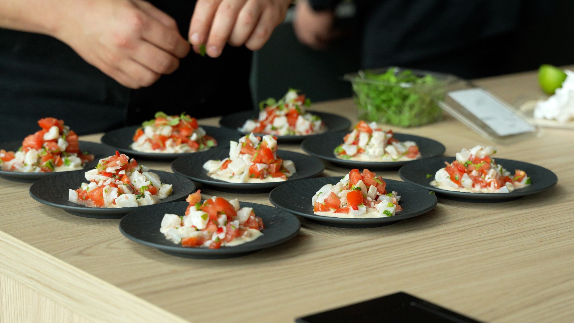 A private chef plating a fish starter on black plates