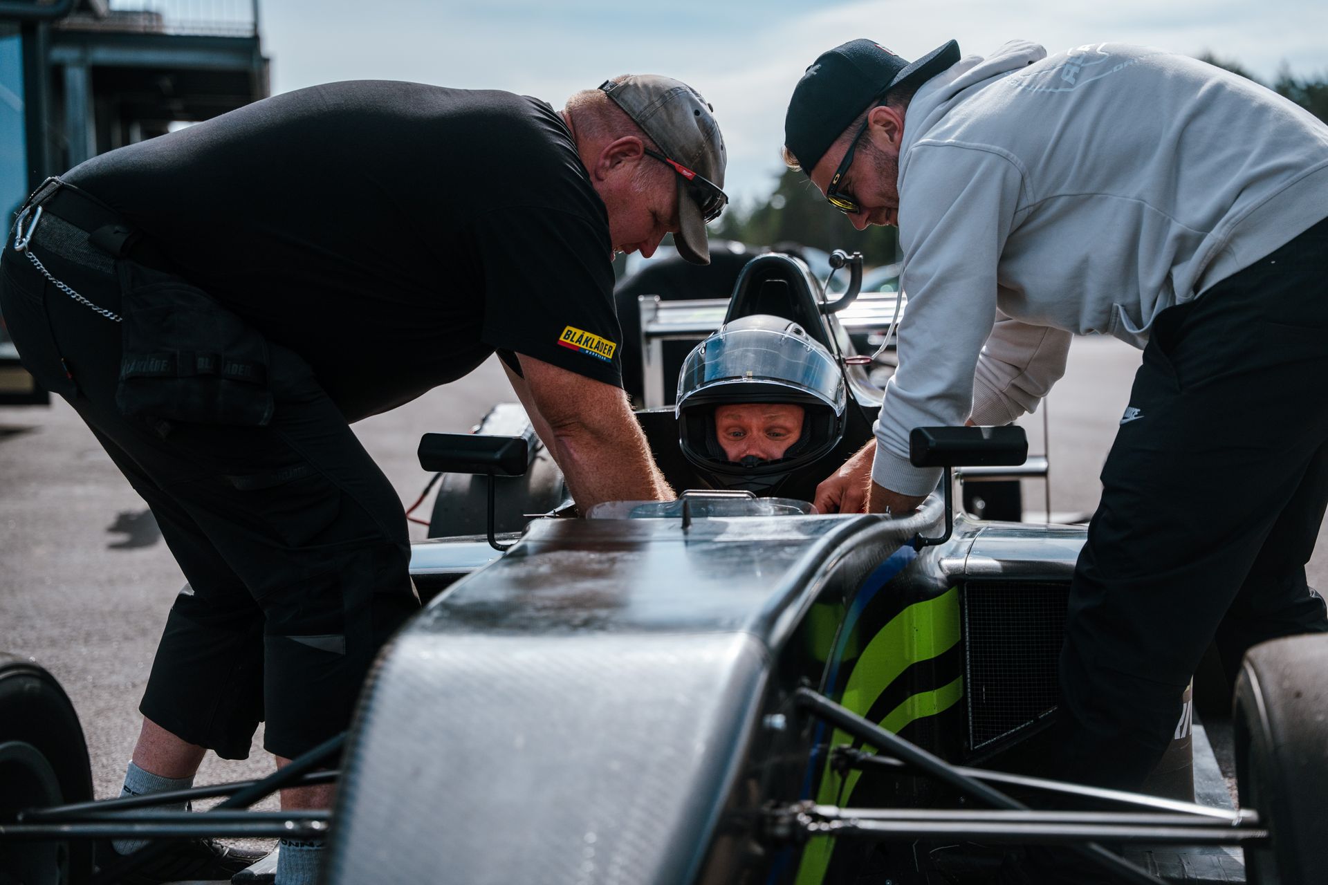 Crew strapping a guest into a single-seater Formula car