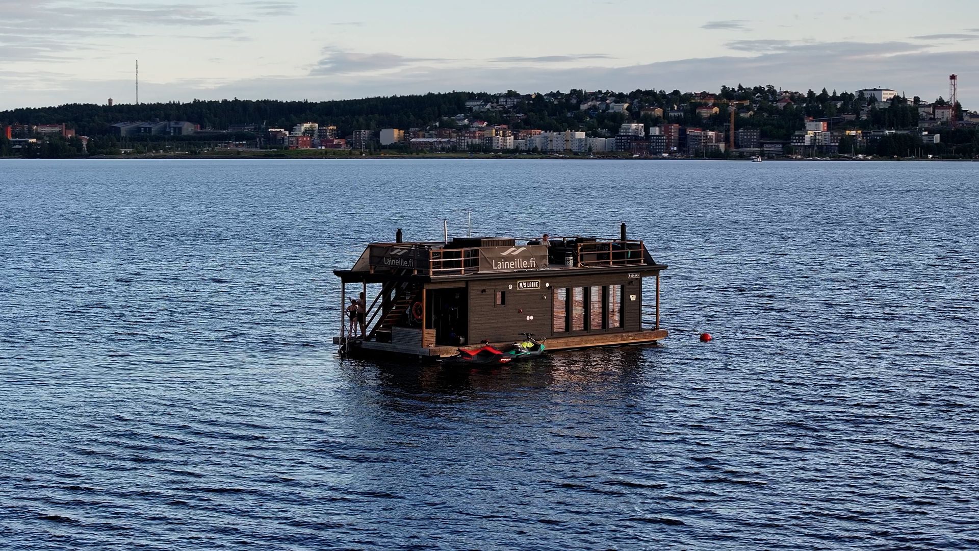 A floating sauna on the lake with jet skis alongside